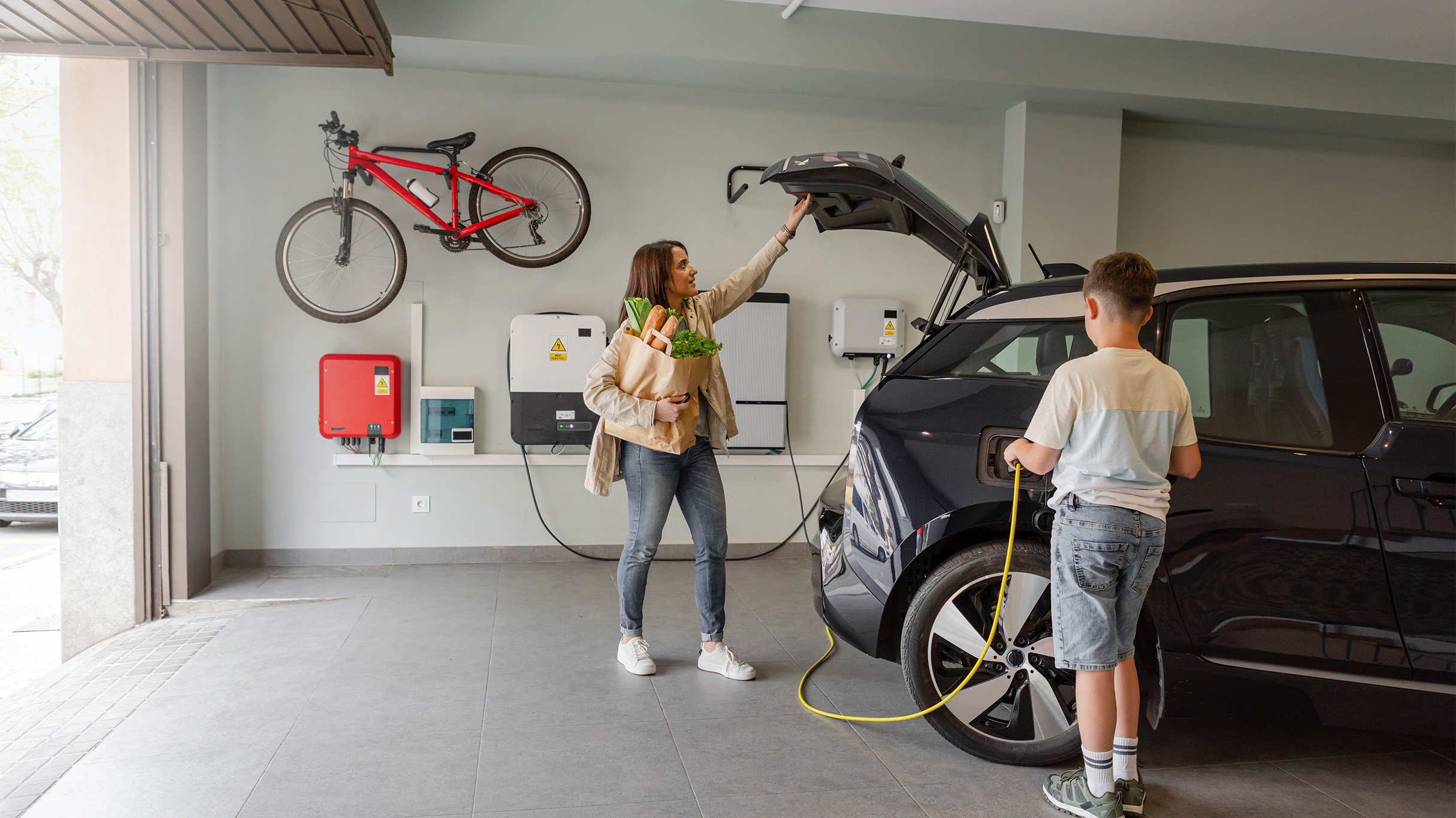 Mother and son charging electric vehicle at home