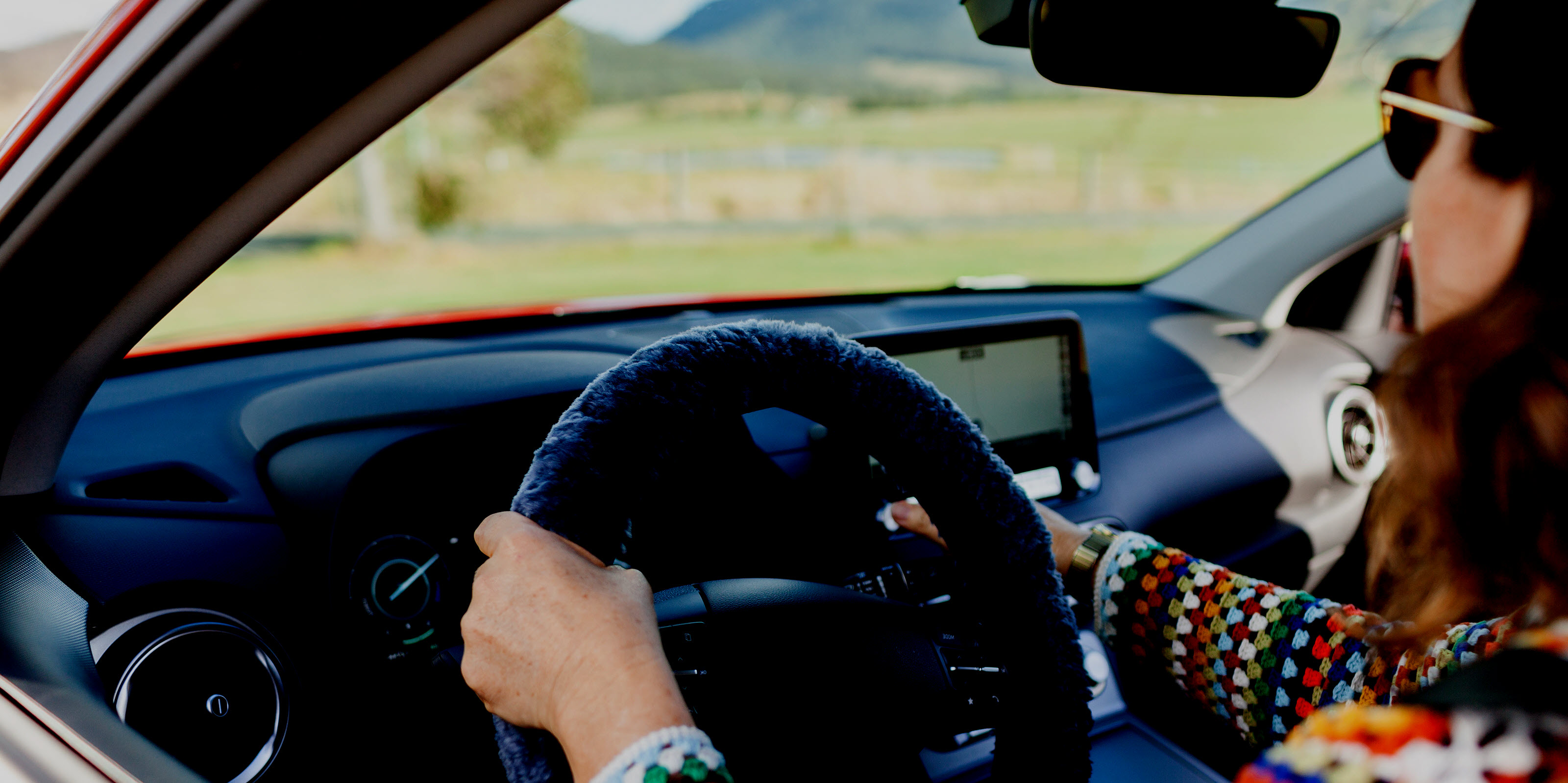 Woman driving a car with a GPS navigation system visible on the dashboard. 