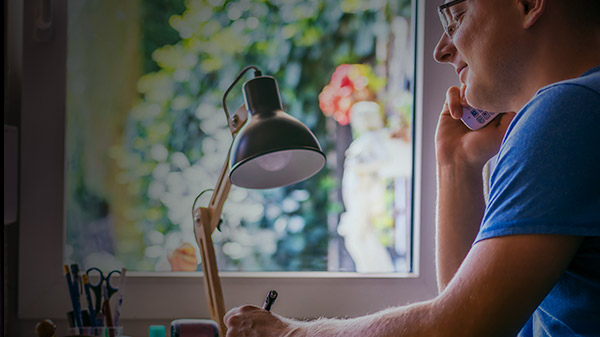 A man on the landline phone writing down information from an expert claims advisor
